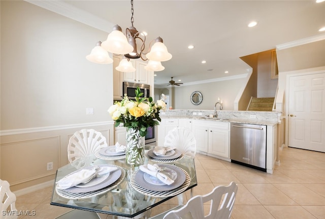 tiled dining room featuring ceiling fan with notable chandelier, ornamental molding, and sink