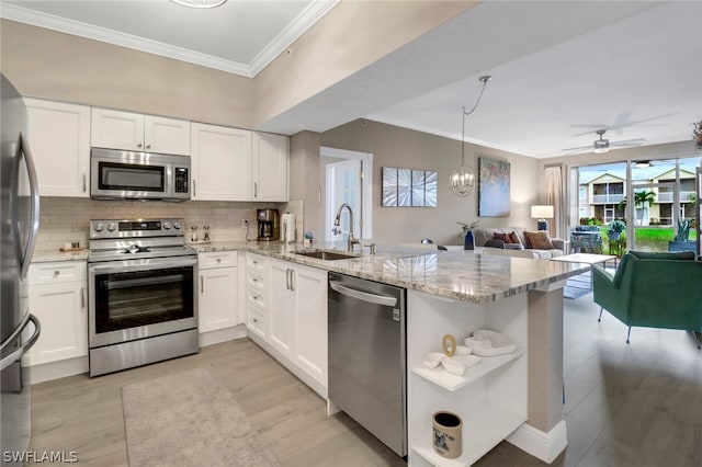 kitchen with appliances with stainless steel finishes, sink, kitchen peninsula, light stone counters, and ceiling fan with notable chandelier