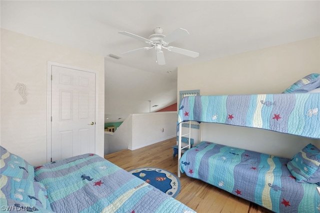 bedroom featuring light wood-type flooring, ceiling fan, visible vents, and lofted ceiling