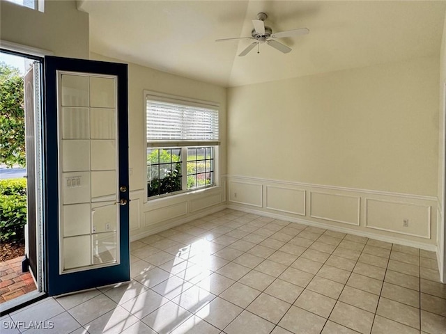 entryway featuring a ceiling fan, a wainscoted wall, a decorative wall, and light tile patterned floors