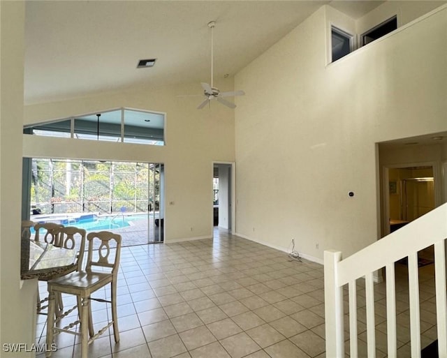 interior space with light tile patterned floors, baseboards, visible vents, a ceiling fan, and high vaulted ceiling