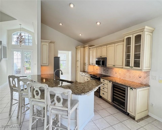 kitchen featuring cream cabinets, beverage cooler, black range with electric stovetop, a sink, and stainless steel microwave