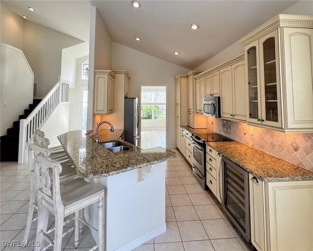 kitchen with appliances with stainless steel finishes, cream cabinetry, a sink, and a kitchen breakfast bar