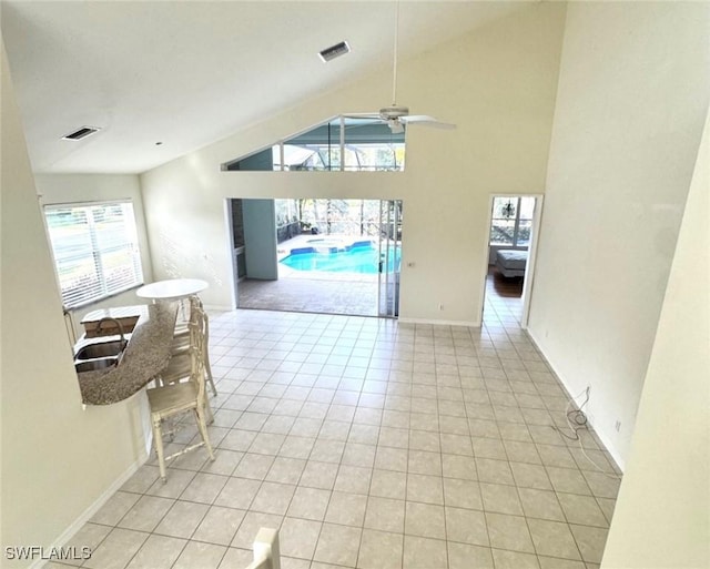 unfurnished dining area featuring light tile patterned floors, high vaulted ceiling, visible vents, and baseboards