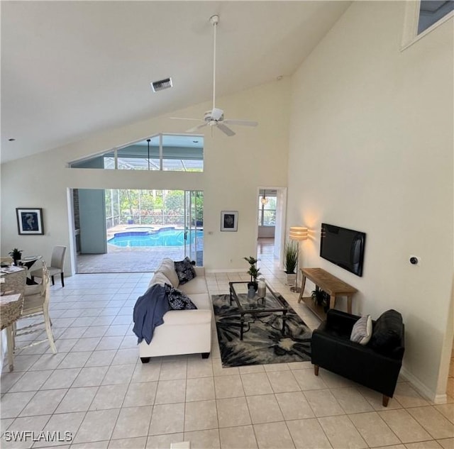 living area featuring light tile patterned floors, high vaulted ceiling, a sunroom, visible vents, and baseboards