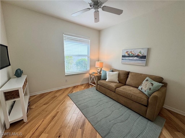 living room with light wood-type flooring, ceiling fan, and baseboards