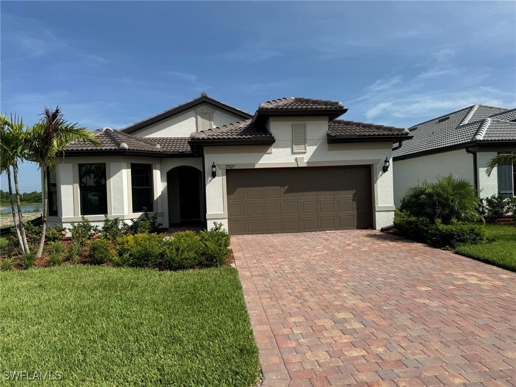 mediterranean / spanish-style house featuring a front yard and a garage