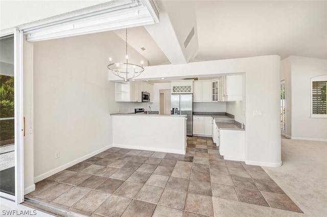 kitchen featuring lofted ceiling, decorative light fixtures, kitchen peninsula, stainless steel appliances, and white cabinets