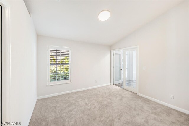 empty room featuring lofted ceiling, light carpet, and french doors