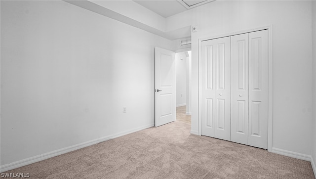 unfurnished bedroom with light colored carpet and a closet