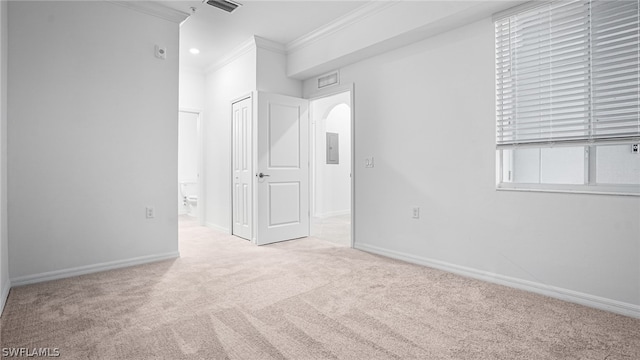 empty room with light colored carpet, ornamental molding, and electric panel