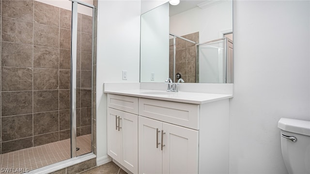 bathroom featuring a shower with door, vanity, tile patterned floors, and toilet