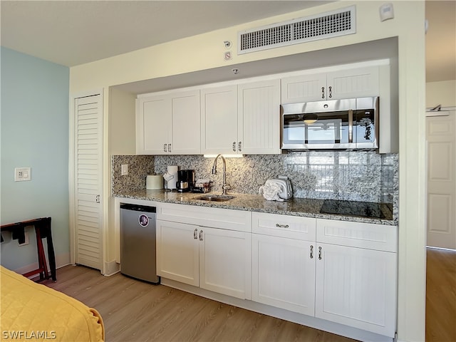 kitchen with white cabinetry, sink, light stone counters, light hardwood / wood-style floors, and black electric cooktop