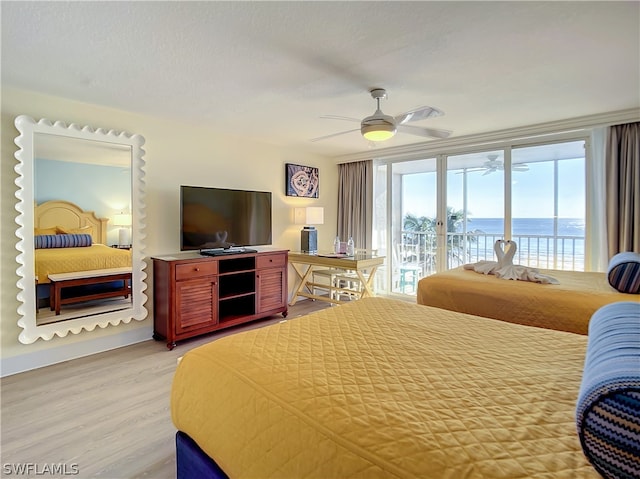 bedroom featuring a textured ceiling, access to outside, ceiling fan, a wall of windows, and light hardwood / wood-style floors