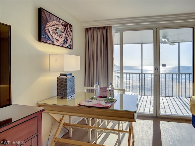 dining room featuring light wood-type flooring, a water view, and ceiling fan