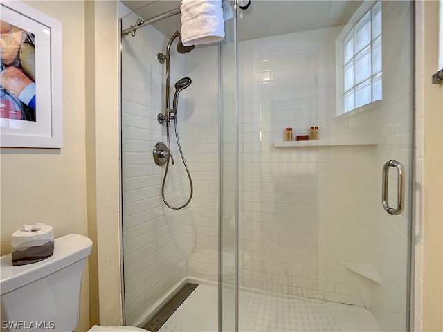 bathroom featuring toilet and a shower with door