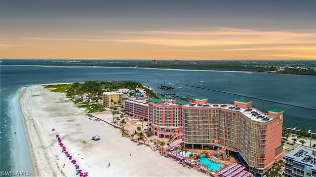 aerial view at dusk with a water view and a view of the beach