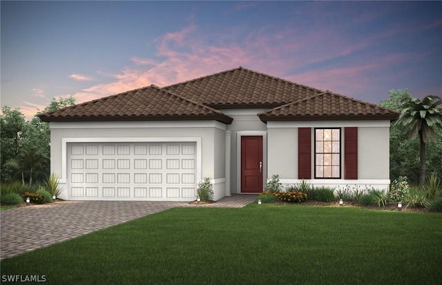 mediterranean / spanish-style home with a tile roof, an attached garage, decorative driveway, a front yard, and stucco siding