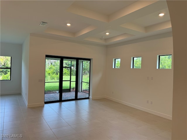 tiled spare room featuring coffered ceiling and a healthy amount of sunlight