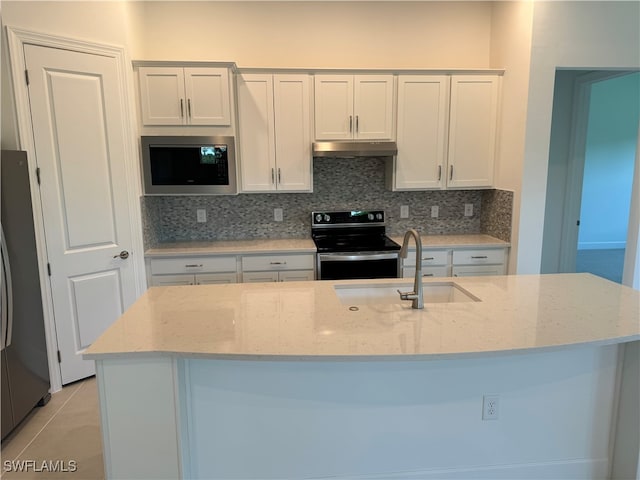 kitchen with light stone counters, stainless steel appliances, and a center island with sink