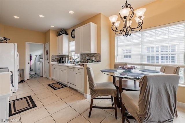 kitchen with tasteful backsplash, white cabinetry, hanging light fixtures, light tile patterned floors, and white appliances