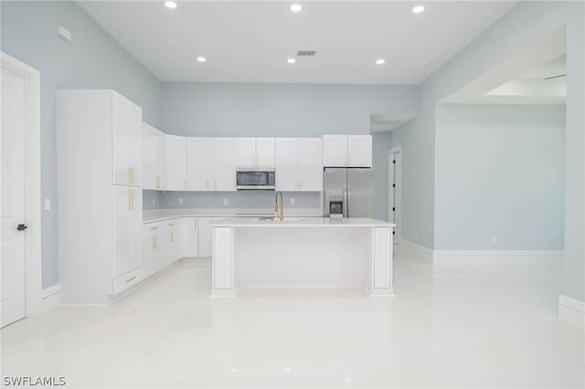 kitchen featuring white cabinets, stainless steel appliances, a kitchen island with sink, and sink