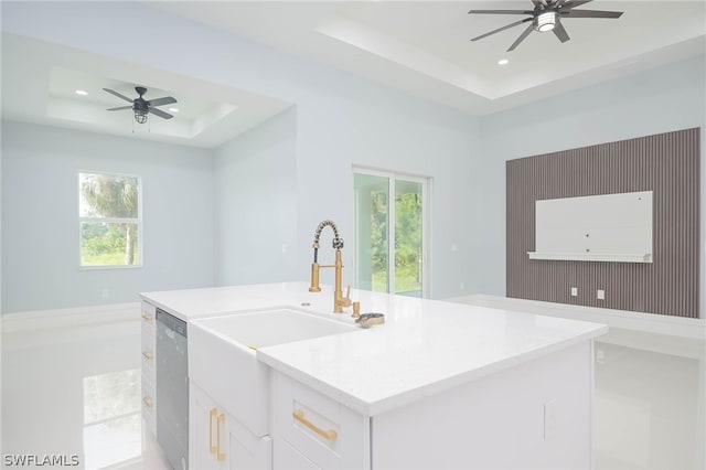 kitchen featuring white cabinetry, light stone countertops, dishwasher, ceiling fan, and a raised ceiling