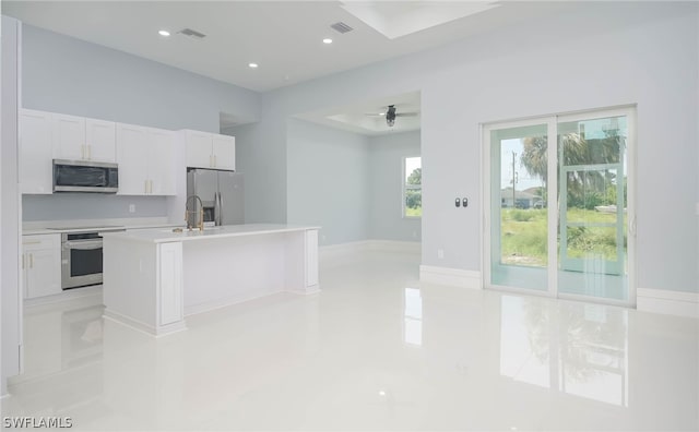 kitchen featuring light tile patterned floors, white cabinets, a kitchen island with sink, appliances with stainless steel finishes, and sink