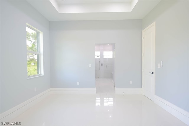 empty room with tile patterned floors and a raised ceiling