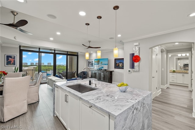 kitchen featuring sink, ceiling fan, white cabinetry, hanging light fixtures, and light stone counters