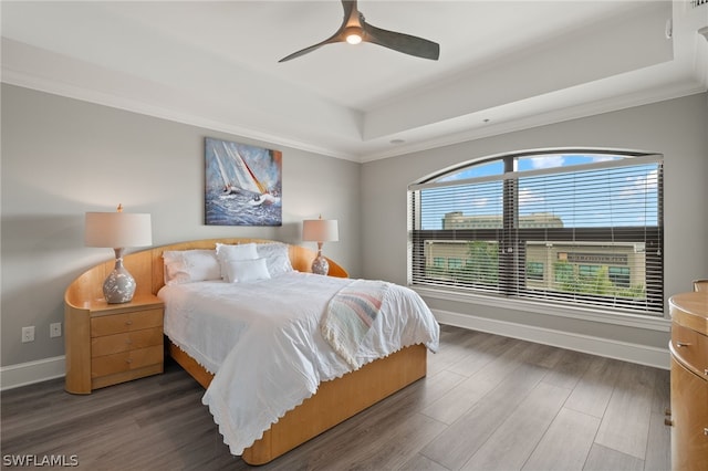 bedroom featuring a tray ceiling, ornamental molding, dark hardwood / wood-style floors, and ceiling fan