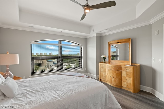 bedroom with wood-type flooring, ornamental molding, ceiling fan, and a tray ceiling