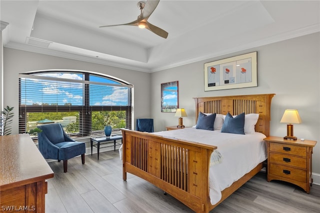 bedroom with ornamental molding, hardwood / wood-style floors, ceiling fan, and a tray ceiling