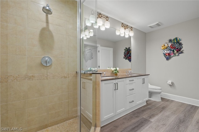 bathroom with vanity, tiled shower, hardwood / wood-style floors, and toilet