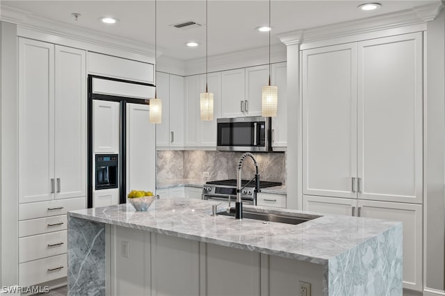 kitchen with sink, white cabinetry, light stone counters, hanging light fixtures, and an island with sink