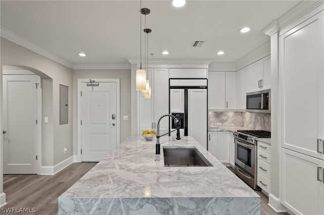 kitchen with a kitchen island with sink, sink, white cabinets, and appliances with stainless steel finishes