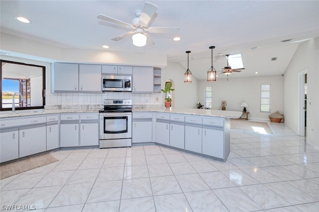 kitchen featuring kitchen peninsula, ceiling fan, appliances with stainless steel finishes, decorative backsplash, and sink