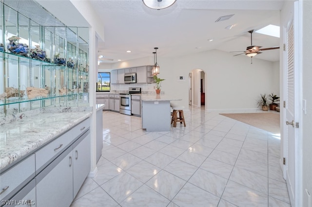 kitchen featuring decorative light fixtures, a kitchen bar, ceiling fan, and stainless steel appliances