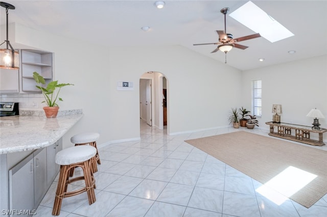 interior space featuring range, hanging light fixtures, light stone countertops, a kitchen bar, and kitchen peninsula