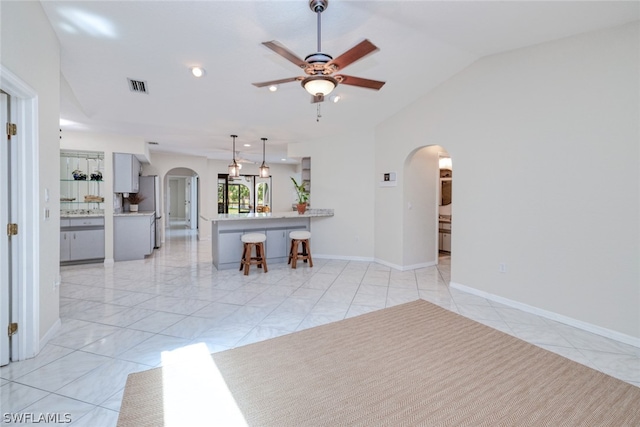 unfurnished living room featuring light tile patterned floors, vaulted ceiling, and ceiling fan