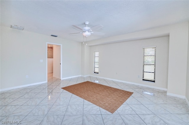 unfurnished room with ceiling fan, light tile patterned floors, and a textured ceiling