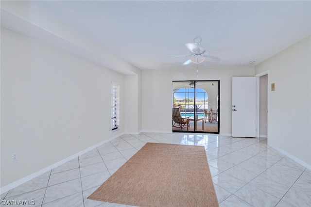 tiled empty room featuring ceiling fan