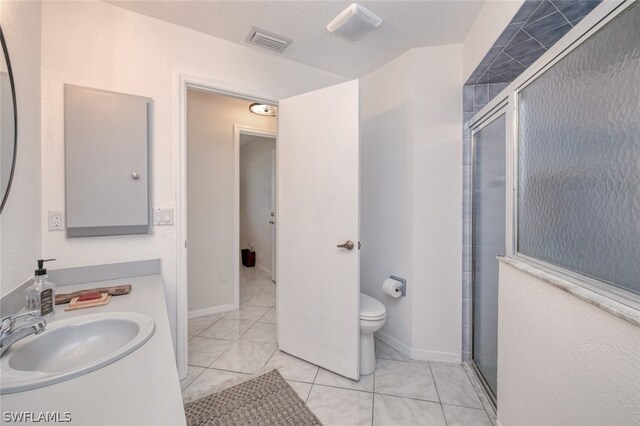 bathroom with a shower with door, vanity, tile patterned flooring, and toilet