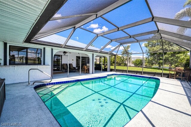 view of pool with glass enclosure, a patio area, and ceiling fan