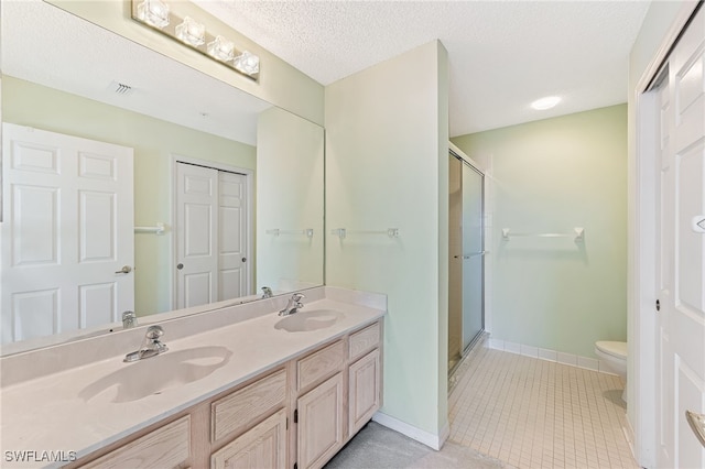 bathroom featuring walk in shower, vanity, a textured ceiling, tile patterned flooring, and toilet