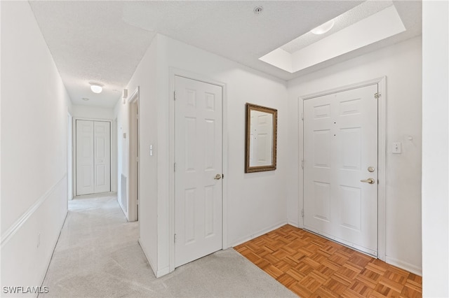 foyer entrance with a textured ceiling and light parquet floors