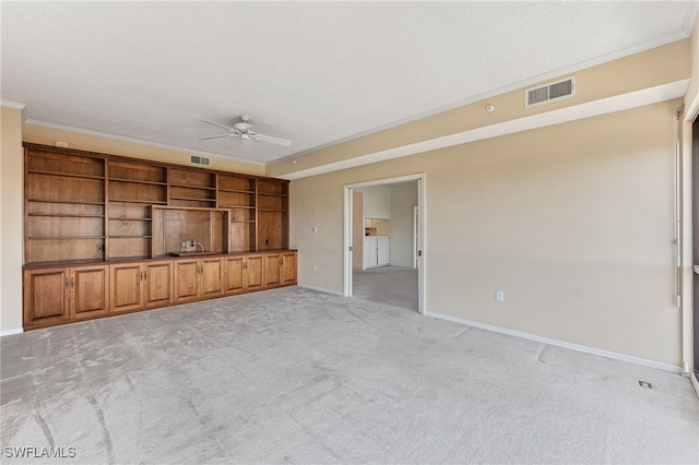 unfurnished living room with light carpet, ceiling fan, a textured ceiling, and ornamental molding