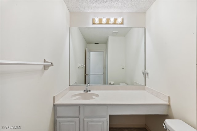 bathroom with toilet, vanity, and a textured ceiling