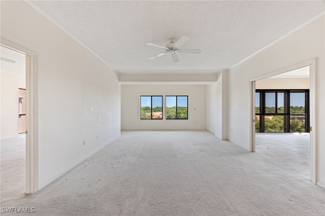 unfurnished room with light carpet, ornamental molding, a textured ceiling, and a ceiling fan