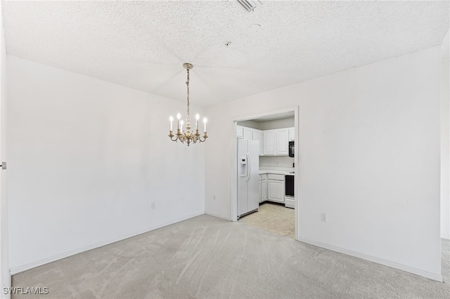 carpeted spare room with a textured ceiling and an inviting chandelier